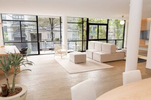 Un salon moderne avec de grandes fenêtres, un canapé, une table basse et une plante en pot.