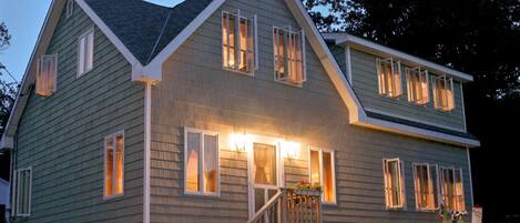 A two-story house with a front porch, a staircase, and a flower bed.