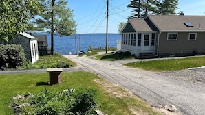 A rural road leading to a small house with a dock by a lake.