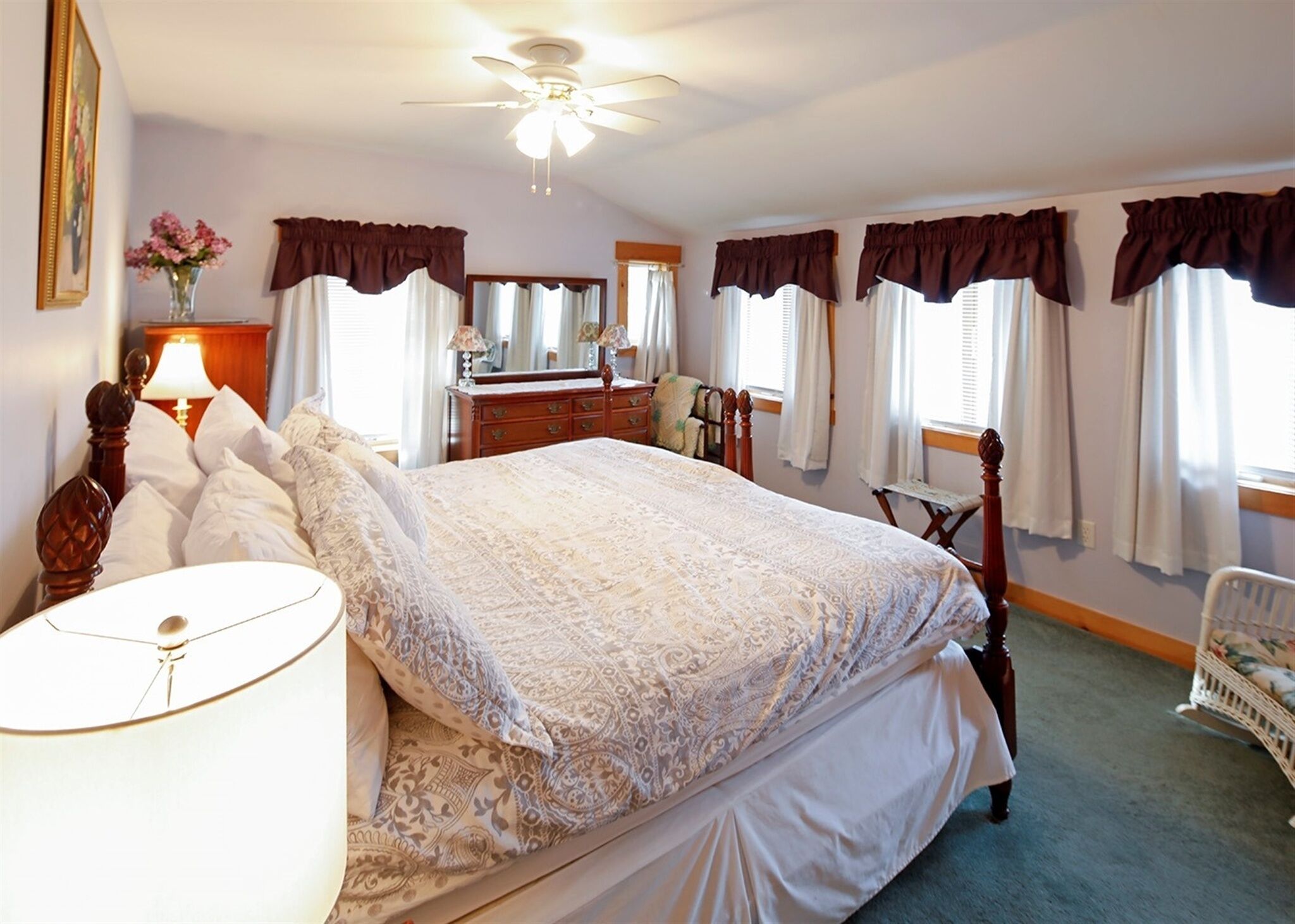 A bedroom with a large bed, a dresser, a vanity, and a chair.