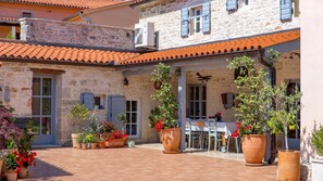 A courtyard with stone buildings, potted plants, and outdoor seating.
