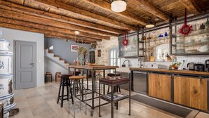 A rustic kitchen with exposed wooden beams, a stone wall, and a bar area with stools. - Rustic Villa Folirantica with pool (Foli)