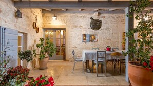 A rustic stone-walled dining area with a table set for two, surrounded by potted plants and a chandelier. - Rustic Villa Folirantica with pool (Foli)
