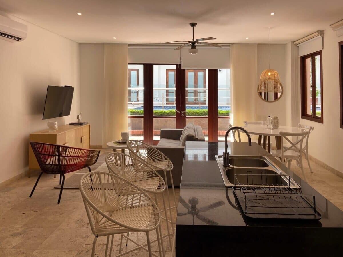Een moderne woonkamer met een eethoek, een televisie op een kast, en uitzicht op de omgeving.