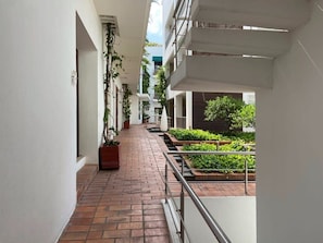Stroll through this serene corridor, lined with lush greenery and leading to a staircase.