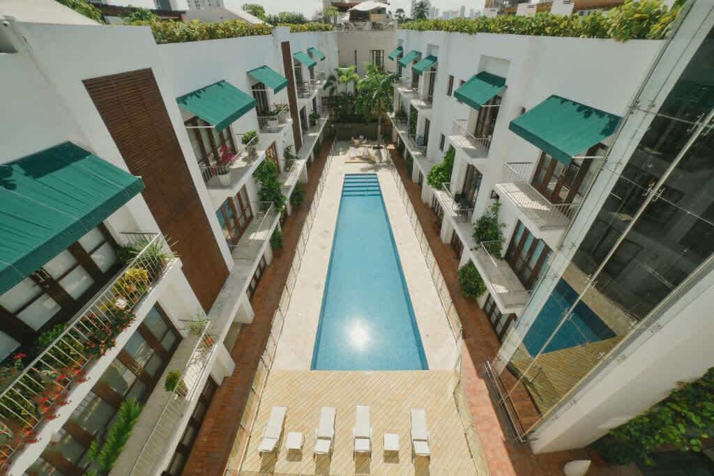 Un hotel moderno con piscina centrale, numerosi balconi e terrazza sul tetto.