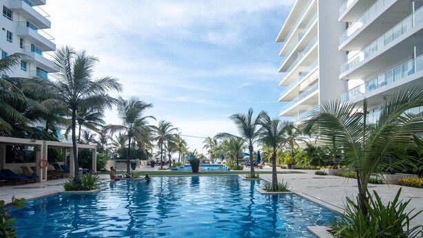 A swimming pool surrounded by palm trees and modern buildings. - w* | Luxury 4BR w/ Private Pool in Morros Epic (Cartagena de Indias)