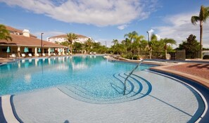 A swimming pool with lounge chairs and umbrellas, surrounded by palm trees and buildings. - New! Vista Cay Luxury Mirage 2 Bedroom Condo by RedAwning (Orlando)