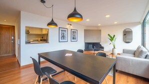 A modern living room with a dining table, black chairs, a grey sofa, and a large window. - w* | Industrial 1BR In Cabrera (Bogotá)