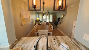 A kitchen with a marble countertop, a sink, and hanging pendant lights.