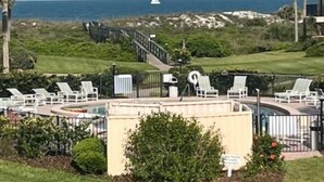 A resort with a pool area, lounge chairs, and a view of the ocean.