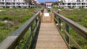 A wooden boardwalk leading to a row of white buildings with red roofs.