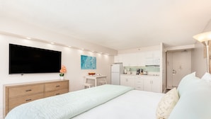 Una camera d'albergo con un letto, una televisione, angolo cottura e bagno.
