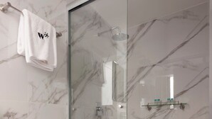 Ein modernes Badezimmer mit Toilette, einer Duschkabine aus Glas und Marmorwänden.