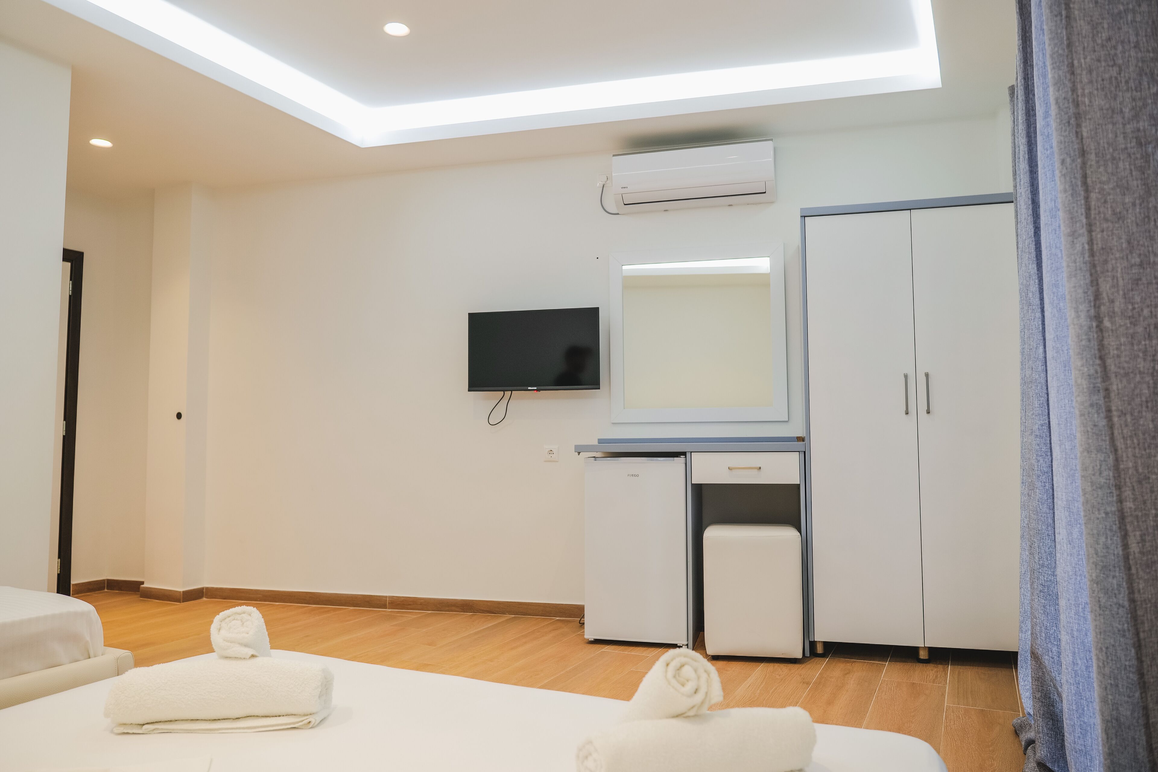 A hotel room with a bed, a desk, a television, a wardrobe, and a ceiling light.