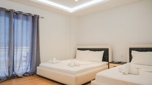 A hotel room with two beds, a nightstand, and a window with curtains. - Foris Rooms (Himarë)