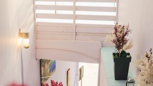 A staircase with white walls and a light blue floor, leading to a door. There are potted plants on the steps and a wall-mounted light fixture. - Foris Rooms (Himarë)