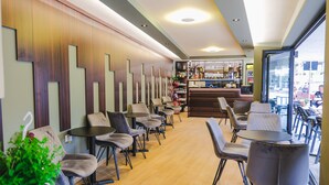 A modern cafe with a bar area, seating arrangements, and a view of the street. - Foris Rooms (Himarë)