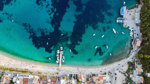 An aerial view of a coastal town with a marina, buildings, and a beach. - Foris Rooms (Himarë)