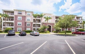 A multi-story residential building with a parking lot in front. - Lakeview Penthouse Elegance 3 Bedroom Condo by RedAwning (Orlando)