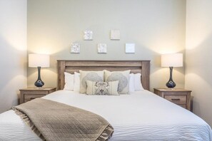 A neatly made bed with a quilted blanket, flanked by two bedside tables with lamps, and a wooden headboard. - Lakeview Penthouse Elegance 3 Bedroom Condo by RedAwning (Orlando)