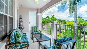 A balcony with a ceiling fan, a table, and two chairs with patterned cushions.