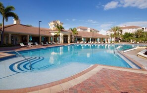 A swimming pool with lounge chairs and umbrellas, surrounded by buildings with a Mediterranean architectural style. - Vista Cay Casa Bonita 3 Bedroom Townhouse by RedAwning (Orlando)