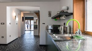 Una cocina moderna con piso blanco y negro moteado, un lavamanos de acero inoxidable y un grifo verde.