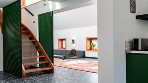 Un interior moderno con una escalera, un sofá, una mesita y una zona de cocina.