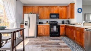 Eine Küche mit Holzausstattung, einem schwarzen Backofen, einer Mikrowelle und einem Kühlschrank.