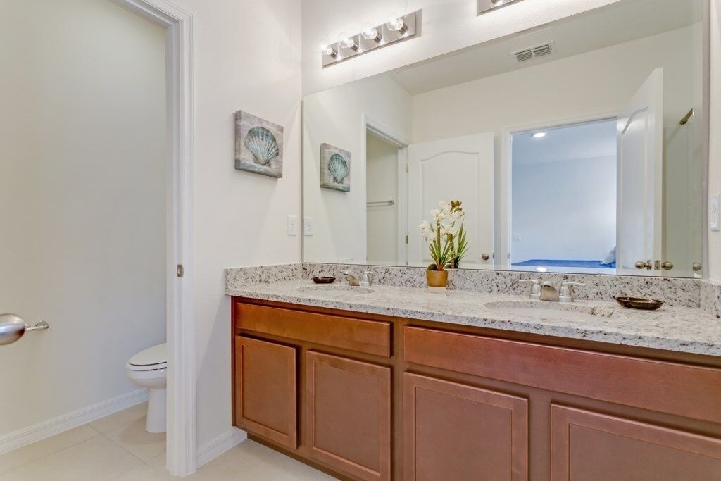 A bathroom with a marble vanity, wooden cabinets, a large mirror, and decorative shells on the wall.