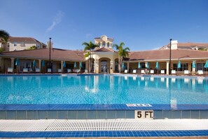 A swimming pool with a 5 ft depth marker, surrounded by lounge chairs and umbrellas.