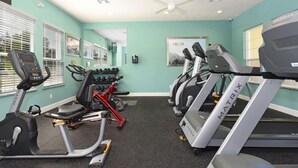 Un gimnasio con cintas de correr, elípticas y bicicletas estáticas.