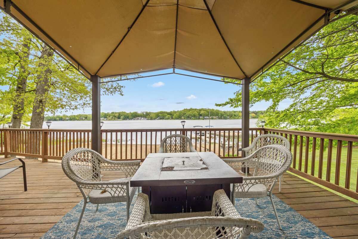 Un espace extérieur abrité, avec une table et des chaises, donnant sur une étendue d’eau.