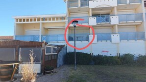 A multi-story building with balconies, a garage, and a sign indicating it is for sale. - Appartement de 2 Chambres Face à L'océan (Mimizan)