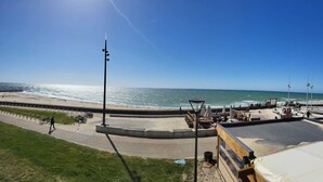 A beachside promenade with a wooden deck, seating areas, and a view of the ocean. - Appartement de 2 Chambres Face à L'océan (Mimizan)