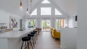 Et moderne køkken med en central ø, barstole og en gul sofa.
