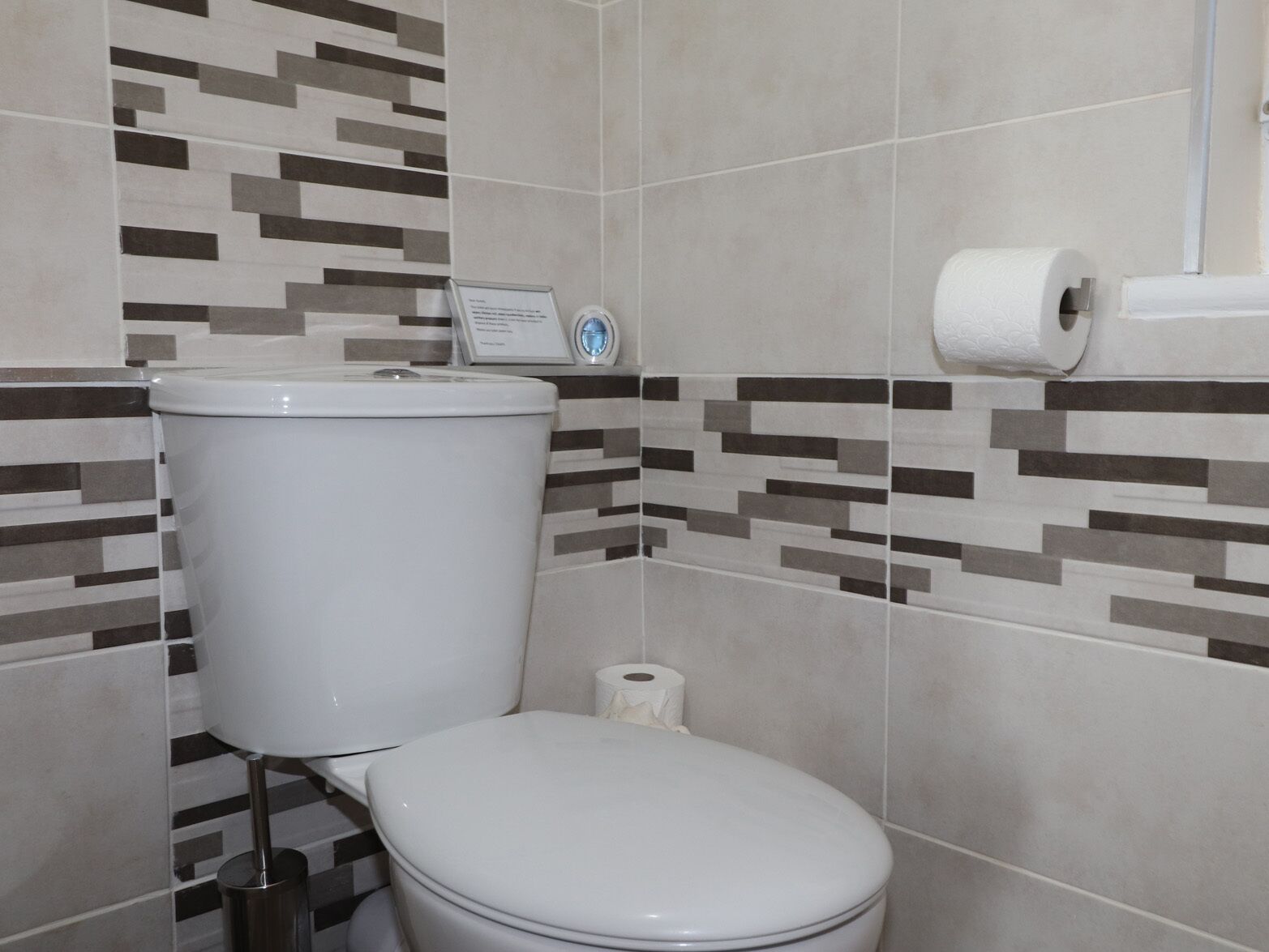 A bathroom with a toilet, a bidet, and a toilet paper holder.