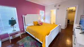 Ein Schlafzimmer mit einem weißen Bett, einem bunten Teppich und einer rosa Wand.
