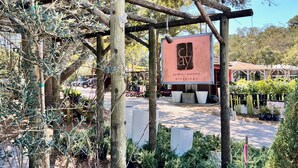 Ein Garten mit einer Holzpergola und einem Schild, auf dem 'Clayby Garten, Keramik, Segen' steht.