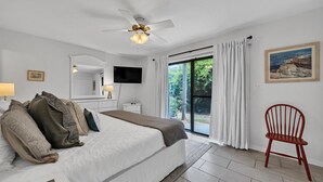 Ein Schlafzimmer mit einem Bett, einem Sessel, einem Fernseher und einem Bild an der Wand.