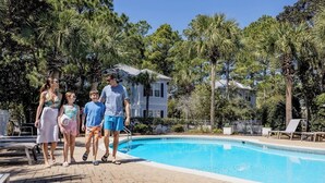 Ein Swimmingpool mit gepflastertem Deck, umgeben von Palmen und einem Haus im Hintergrund.