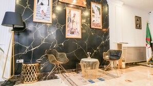 A modern lobby with a black marble wall, framed artwork, and contemporary furniture.