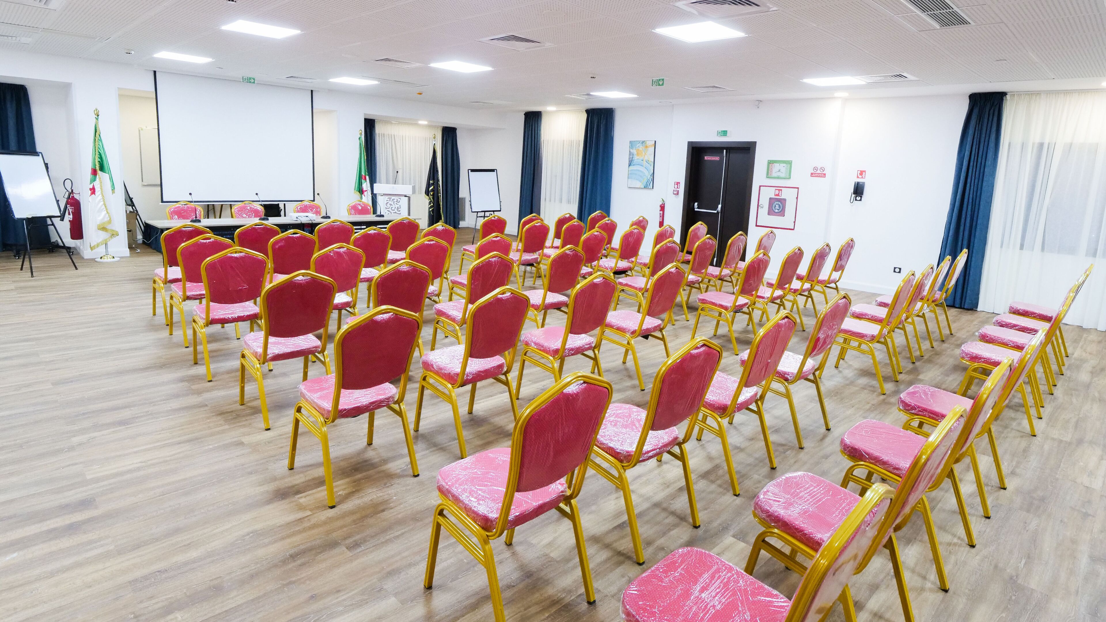 Ein Konferenzraum mit Reihen von Stühlen, einer Tafel und einem Rednerpult.