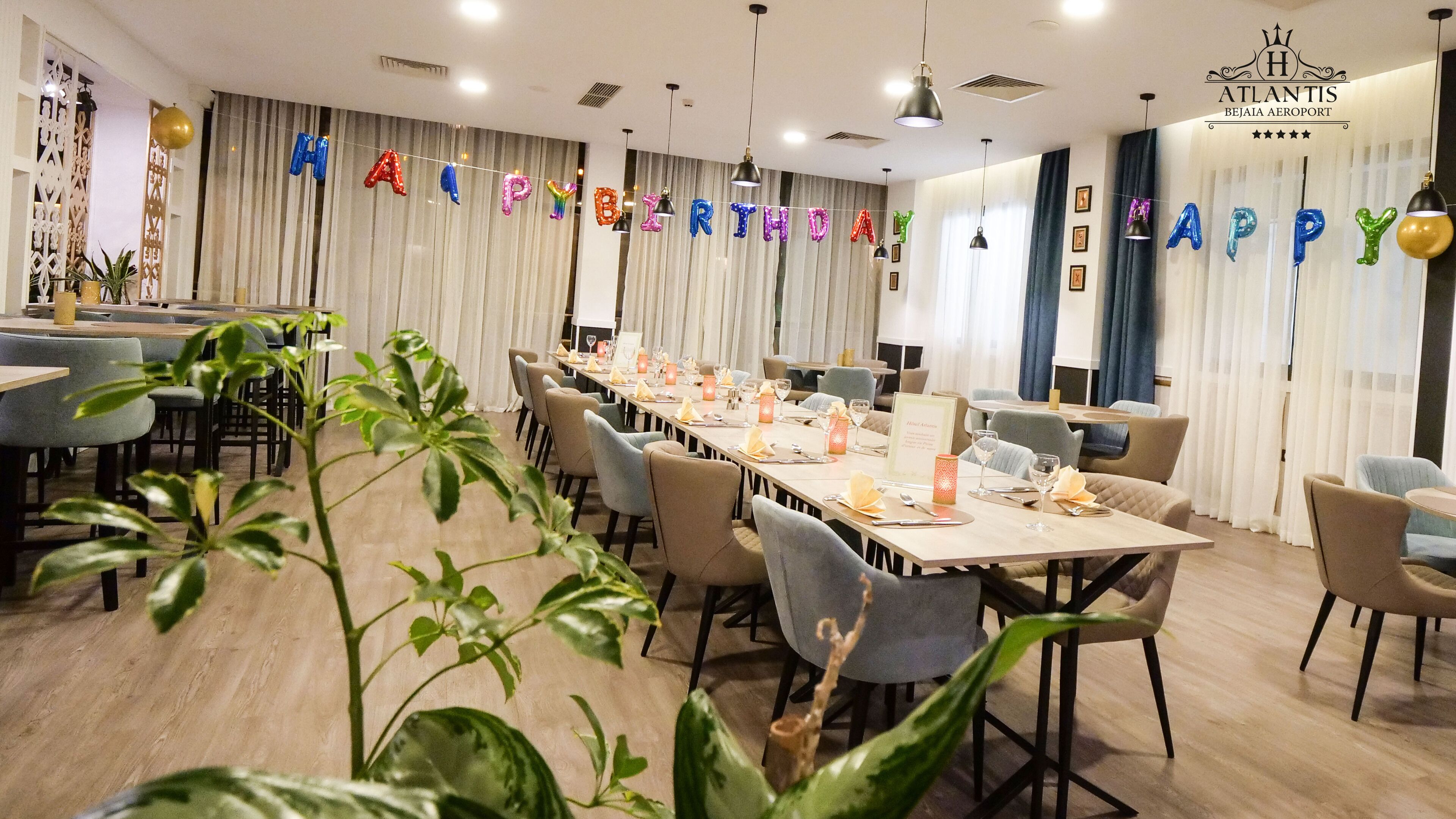 A spacious dining area with long tables, chairs, and a 'Happy Birthday' banner.