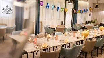 A restaurant with a long table set for a birthday celebration, featuring balloons spelling "HAPPY BIRTHDAY" and a "H" balloon.