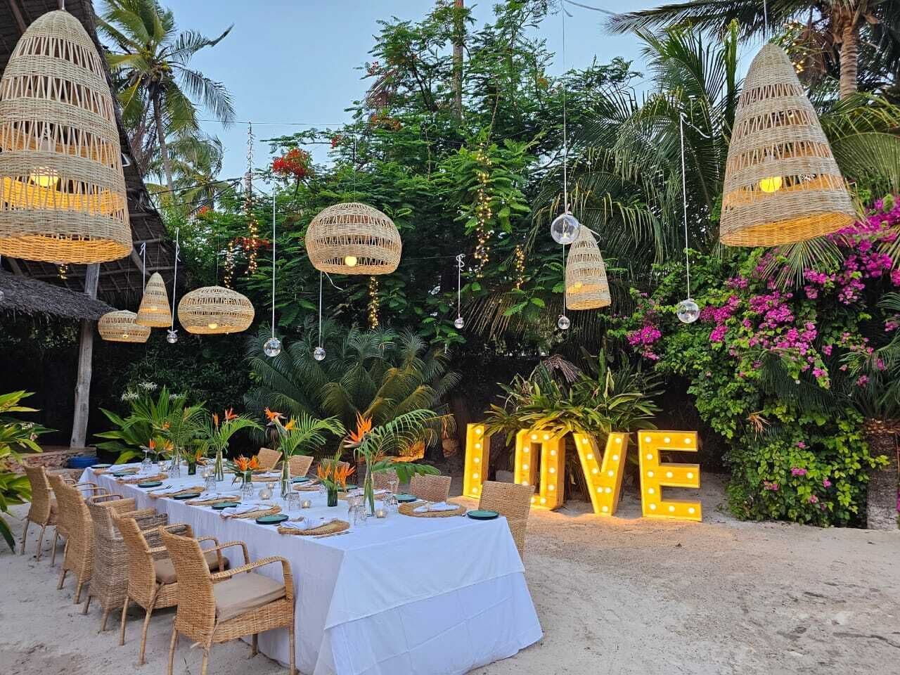 An outdoor dining setup with wicker chairs, a white tablecloth, and a 'LOVE' sign.