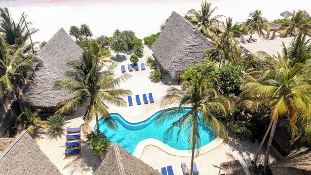 A resort with a swimming pool surrounded by palm trees and thatched-roof huts. - Marafiki Beach Hotel & Spa (Matemwe)