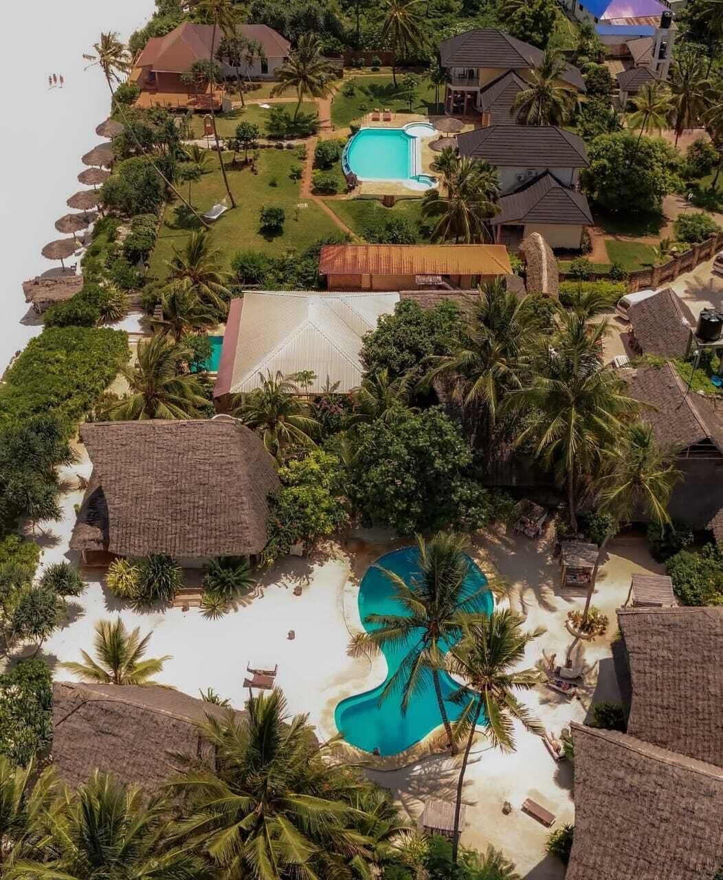Vista aérea de un resort con varias piscinas, palmeras y zonas de playa.