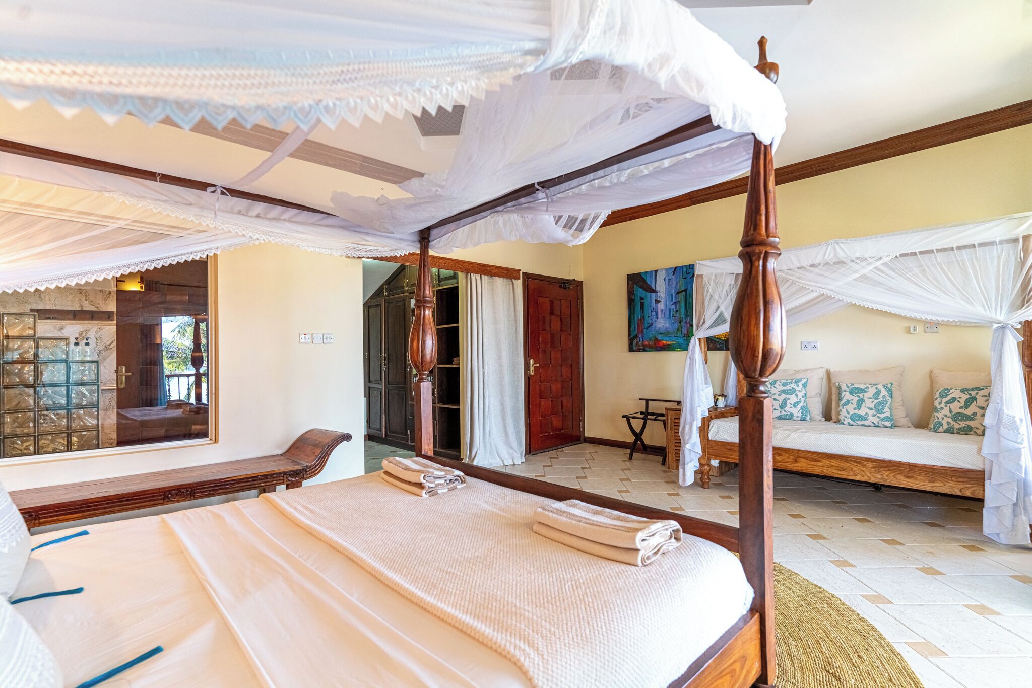 A four-poster bed with a canopy, a sofa with cushions, and a small table.
